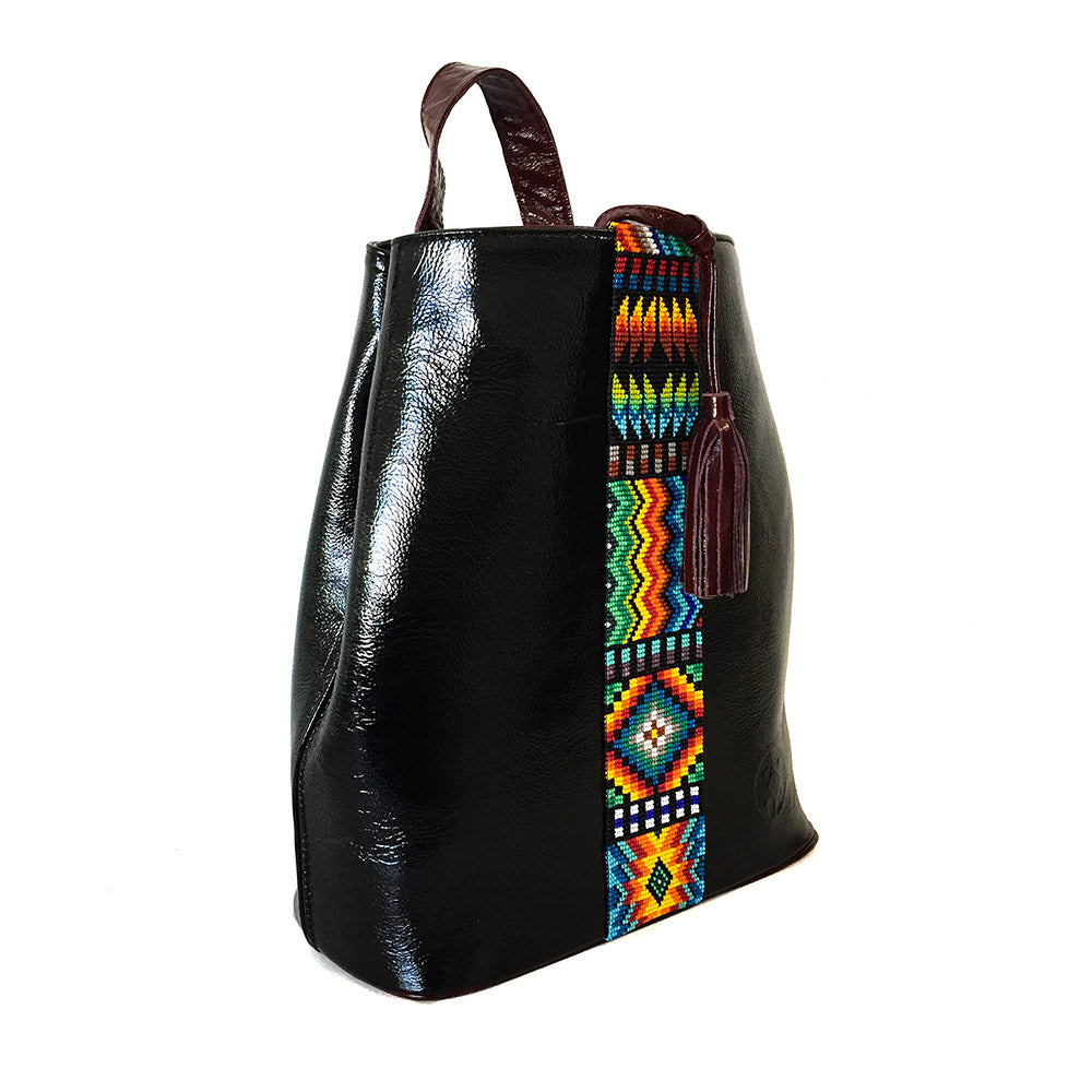 Mochila Backpack de piel para mujer de charol negro con cinta artesanal de chaquira. Vista 3/4
