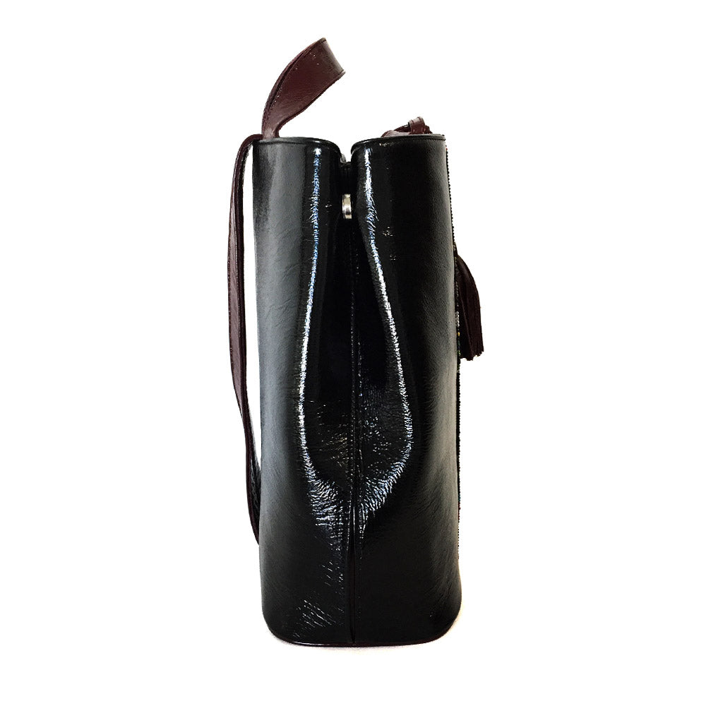 Mochila Backpack de piel para mujer de charol negro con cinta artesanal de chaquira. Vista lateral